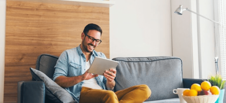 Homme regardant tablette salon heureux de ne pas perdre sa caution